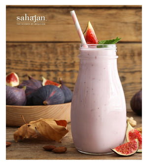 Almond fig smoothie image with fresh figs in a bowl in the background. The Sahajan logo is in the upper left corner. 